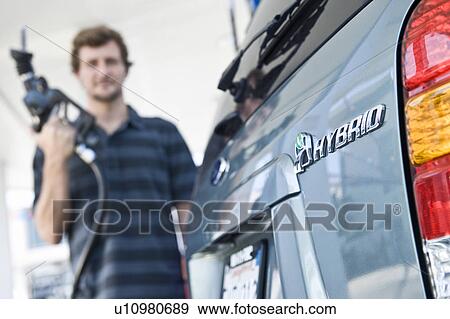 Stock Photo - Man refueling hybrid car. Fotosearch