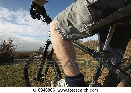 Man riding mountain bike in countryside mid section View Large Photo Image Stock Photograph - Man riding mountain bike in countryside mid section. Fotosearch