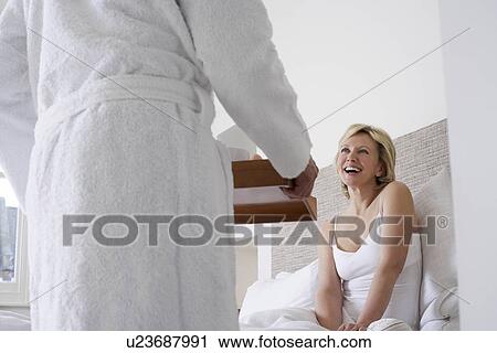 Stock Image - Man serving breakfast to woman in bed. Fotosearch