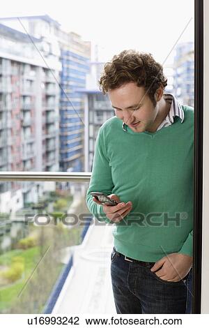 Man text messaging on balcony View Large Photo Image Stock Image - Man text messaging on balcony. Fotosearch