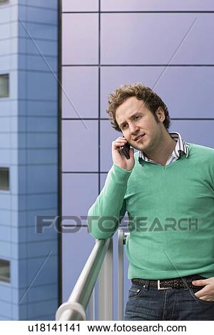 Man using mobile phone on balcony View Large Photo Image Stock Image - Man using mobile phone on balcony. Fotosearch