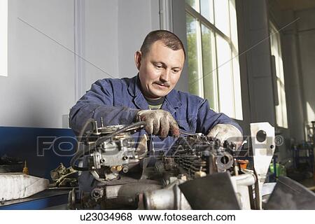 Stock Photo - Mechanic Working on Motor. Fotosearch