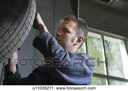 Stock Image - Mechanic Working on Tire. Fotosearch