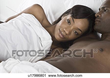 Mid adult couple lying in bed View Large Photo Image Stock Image - Mid adult couple lying in bed. Fotosearch