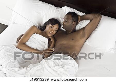 Stock Photo - Mid adult couple lying in bed. Fotosearch