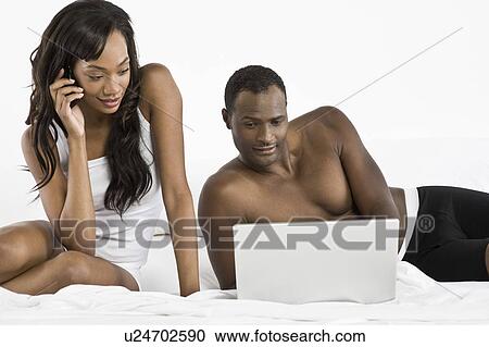 Mid adult couple using laptop in bedroom View Large Photo Image Stock Image - Mid adult couple using laptop in bedroom. Fotosearch