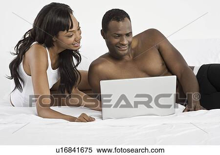 Mid adult couple using laptop in bedroom View Large Photo Image Stock Photography - Mid adult couple using laptop in bedroom. Fotosearch