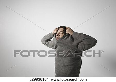 Mid-adult man pulling sweater over head View Large Photo Image Picture - Mid-adult man pulling sweater over head. Fotosearch