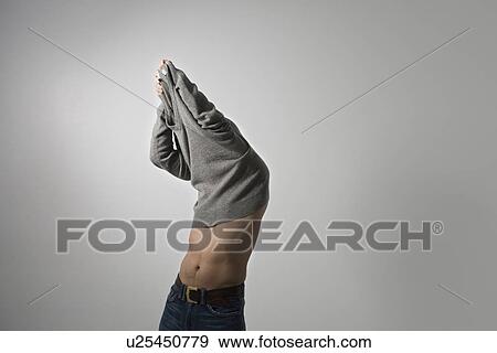 Stock Photo - Mid-adult man pulling sweater over head. Fotosearch