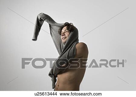 Picture - Mid-adult man putting on sweater. Fotosearch