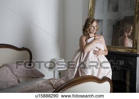 Stock Image - Mid adult woman getting up from bed. Fotosearch