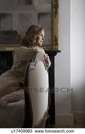 Mid adult woman leaning on chair View Large Photo Image Stock Image - Mid adult woman leaning on chair. Fotosearch