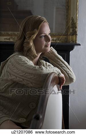 Mid adult woman leaning on chair View Large Photo Image Stock Photograph - Mid adult woman leaning on chair. Fotosearch