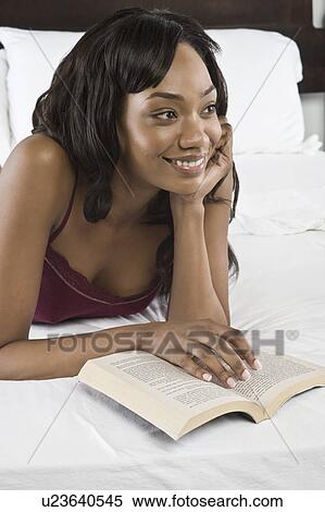 Mid adult woman lying on bed and reading book View Large Photo Image Stock Photography - Mid adult woman lying on bed and reading book. Fotosearch