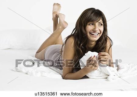 Mid adult woman lying on bed View Large Photo Image Stock Image - Mid adult woman lying on bed. Fotosearch