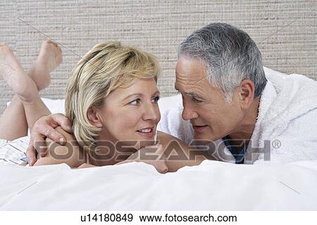 Middle-aged couple lying on bed talking View Large Photo Image Stock Photo - Middle-aged couple lying on bed talking. Fotosearch