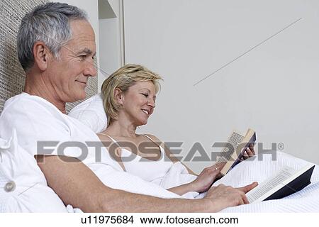 Middle-aged couple reading books in bed View Large Photo Image Picture - Middle-aged couple reading books in bed. Fotosearch