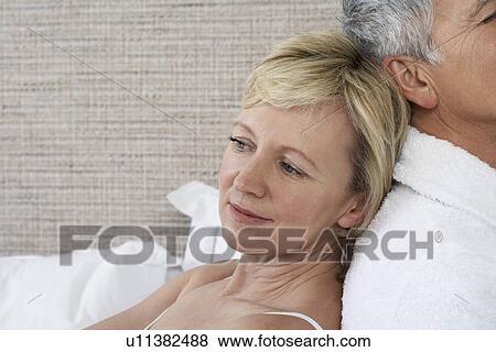 Middle-aged couple sitting back to back in bedroom close-up View Large Photo Image Stock Photo - Middle-aged couple sitting back to back in bedroom close-up. Fotosearch