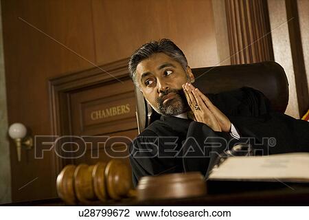 Stock Image - Middle-aged judge in a courtroom. Fotosearch