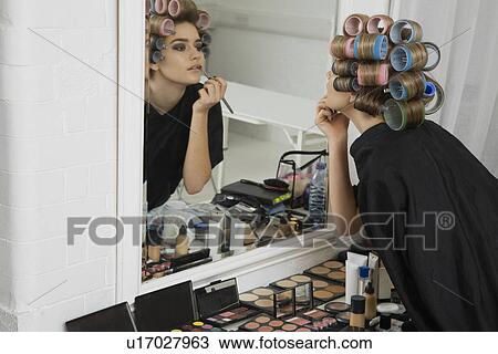 Stock Image - Model in Hair Curlers Applying Lip Gloss. Fotosearch