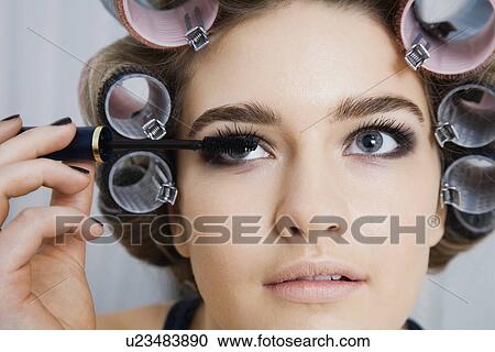 Stock Image - Model in Hair Curlers Applying Mascara. Fotosearch