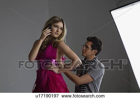 Model on Cell Phone While Designer Adjusts Dress View Large Photo Image Stock Photo - Model on Cell Phone While Designer Adjusts Dress. Fotosearch