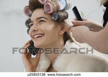 Model on Cell Phone While Having Hair Curled View Large Photo Image Stock Photo - Model on Cell Phone While Having Hair Curled. Fotosearch