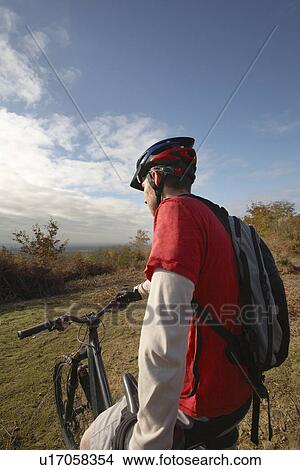Picture - Mountain biker looking at view in countryside. Fotosearch