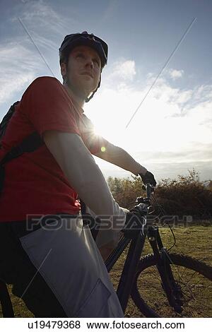 Stock Photo - Mountain biker looking at view in countryside. Fotosearch