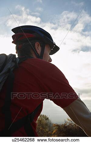 Stock Photo - Mountain biker looking at view in countryside. Fotosearch