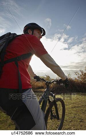Stock Photograph - Mountain biker looking at view in countryside. Fotosearch