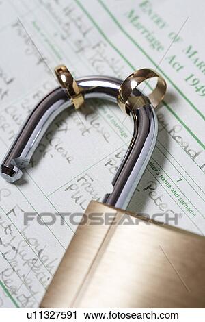 Stock Image - Padlock with two wedding rings on marriage act close-up. Fotosearch