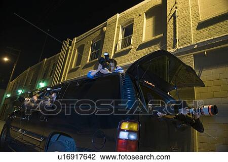 Stock Image - Paparazzi photographer in car. Fotosearch