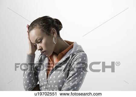 Stock Image - Pensive young woman holding hand on head close-up view. Fotosearch