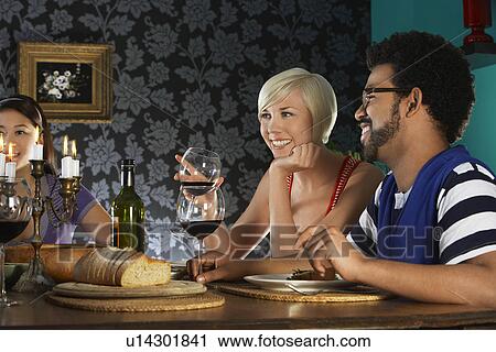 Stock Image - people sitting at dining table. Fotosearch