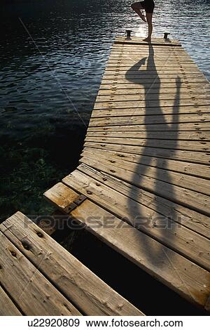 Stock Photo - Person exercising on jetty. Fotosearch