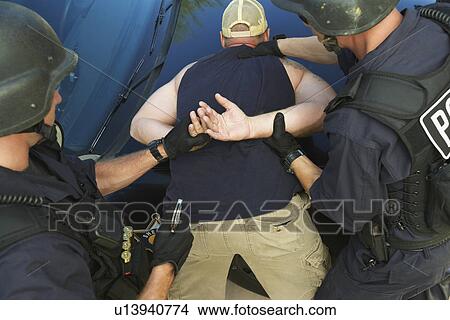 Picture - Police man putting handcuffs on criminal. Fotosearch