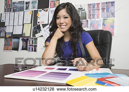 Stock Photo - Portrait of female fashion designer working at desk. Fotosearch