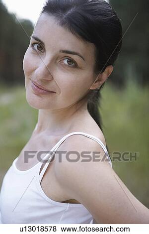 Stock Photo - Portrait of mid-adult woman looking over shoulder. Fotosearch
