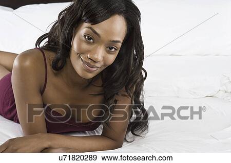 Stock Photo - Portrait of mid adult woman lying on bed. Fotosearch
