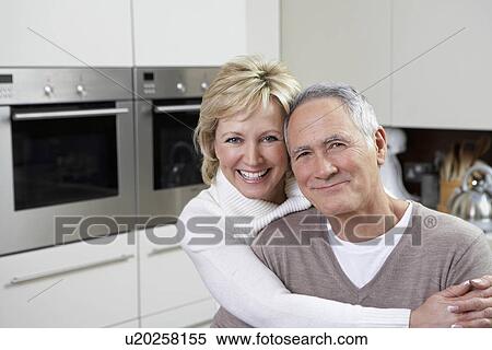 Stock Photography - Portrait of middle-aged couple in kitchen. Fotosearch