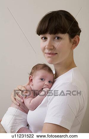 Stock Image - Portrait of mother hugging her newborn baby studio shot. Fotosearch