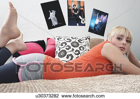 Stock Image - Portrait of teenage girl (16-17) lying on bed. Fotosearch