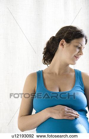 Stock Image - Pregnant woman holding stomach. Fotosearch