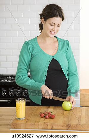 Stock Photo - Pregnant woman preparing food in kitchen. Fotosearch