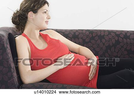 Pregnant woman relaxing on sofa View Large Photo Image Picture - Pregnant woman relaxing on sofa. Fotosearch