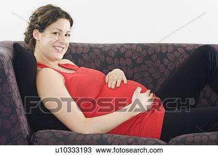Stock Image - Pregnant woman relaxing on sofa portrait. Fotosearch