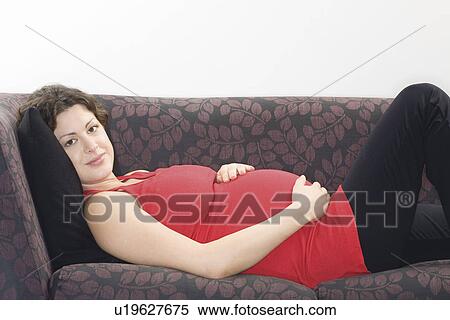 Stock Photography - Pregnant woman relaxing on sofa portrait. Fotosearch