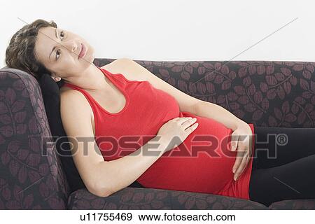 Stock Photo - Pregnant woman relaxing on sofa. Fotosearch
