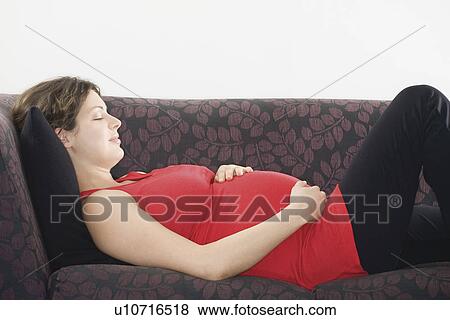 Stock Photo - Pregnant woman sleeping on sofa. Fotosearch